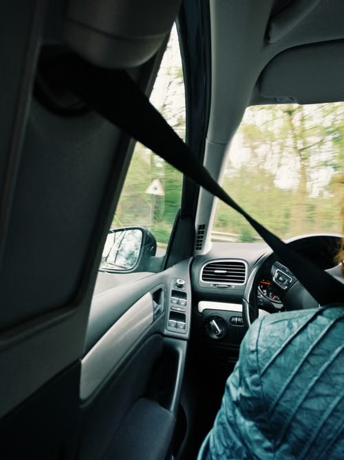 View across a moving car interior with the seat belt drawn across the front passenger seat